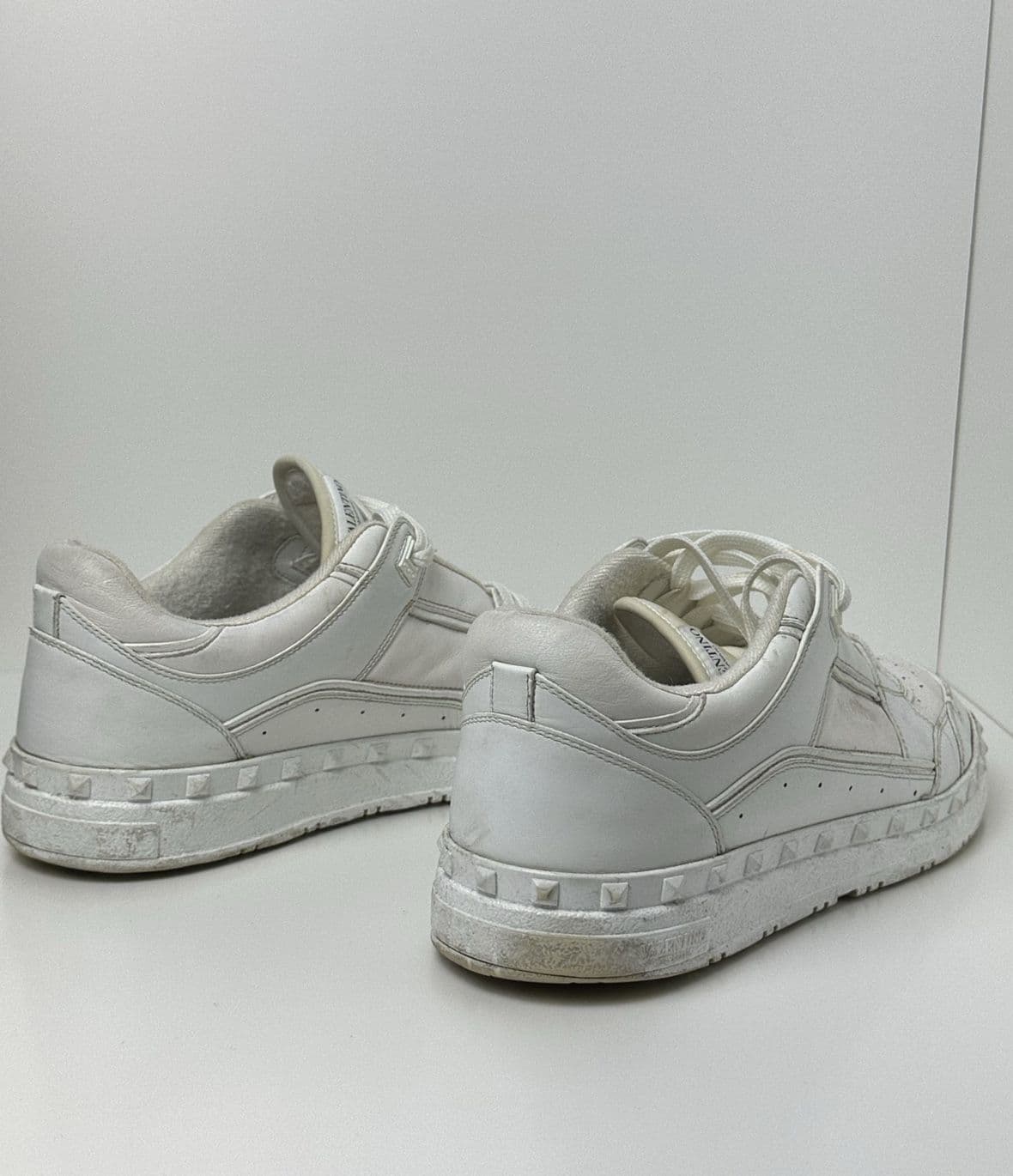 Sneakers albi din piele, murdari pe talpă, înainte